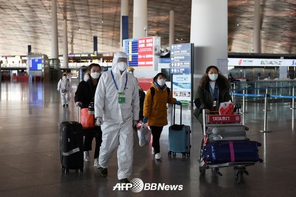 한 공항 직원이 2020년 3월 27일 베이징 수도공항의 텅 빈 출국장을 통해 승객들을 호송하고 있다.ⓒAFPBBNews