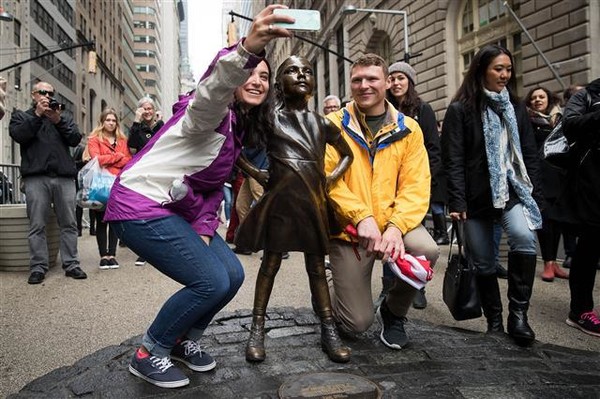 세계여성의 날을 기념해 세운 뉴욕 월가의 ‘두려움 없는 소녀상’을 사이에 두고 관광객들이 기념촬영을 하고 있다.