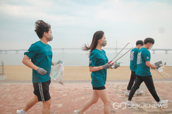 지난 26일 부산 광안리해수욕장 일대에서 부티플 ‘줍줍레이싱’에 참여한 부산 청년들이 조깅을 하며 쓰레기를 줍는 환경 운동인 플로깅을 하고 있다./부티플 제공