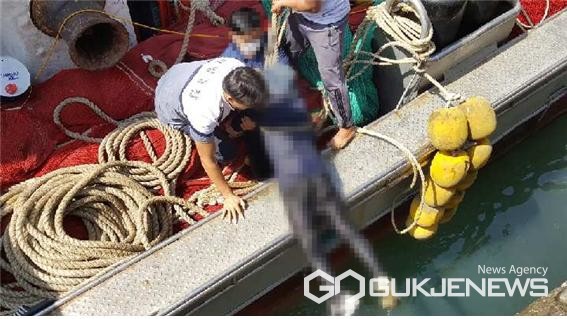 충남 태안해양경찰서 신진파출소 순찰팀 대원이 어선 선원들과 함께 호줄에 매달린 50대 남성을 배 위로 끌어올리고 있다. (©태안해경 제공)