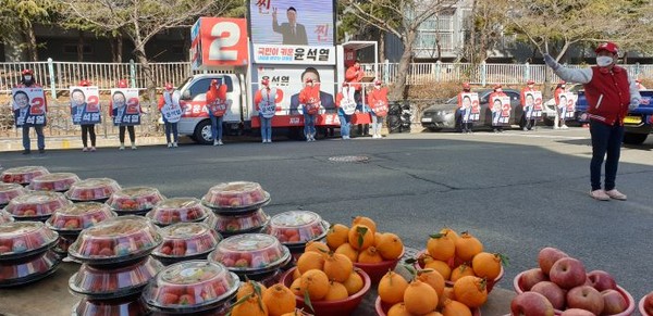 지난 2월 24일 진해구 용원장날 시장터, 과일바구니가 수북이 쌓인 속에서 박춘덕 시의원의 사회 속에서 유세가 한창이다.. (사진=오웅근 기자)