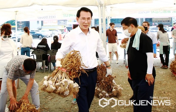 이완섭 충남 서산시장이 지난 2일 농산물 직거래 특판전이 열리는 서산중앙호수공원 주차장을 방문해 서산육쪽마늘을 나르는 등 지역 농산물 판매를 돕고 있다. (사진 = 서산시 제공)