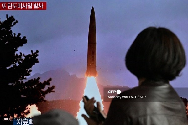 19일 서울 기차역에서 한 여성이 북한의 미사일 시험 발사 영상이 담긴 뉴스 방송을 보여주는 텔레비전 앞을 지나가고 있다. 사진제공/AFP통신
