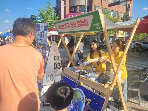  해양환경운동단체인 '포항플로깅' 한 회원이 자녀와 함께 부스를 찾은 아버지에게 해양향쓰레기 정화의 필요성이 담긴 책자를 건네주고 있다. (사진 = 강동진 기자)
