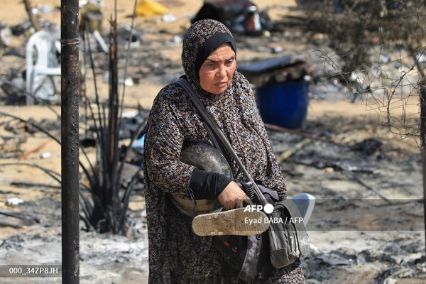 이스라엘과 팔레스타인 무장단체 하마스 간 전쟁이 계속되고 있는 가운데 29일(현지시간) 가자지구 남부 라파의 알마와시 지역에서 이스라엘의 공격 이후 한 여성이 소지품을 들고 걸어가고 있다. 사진제공/AFP통신