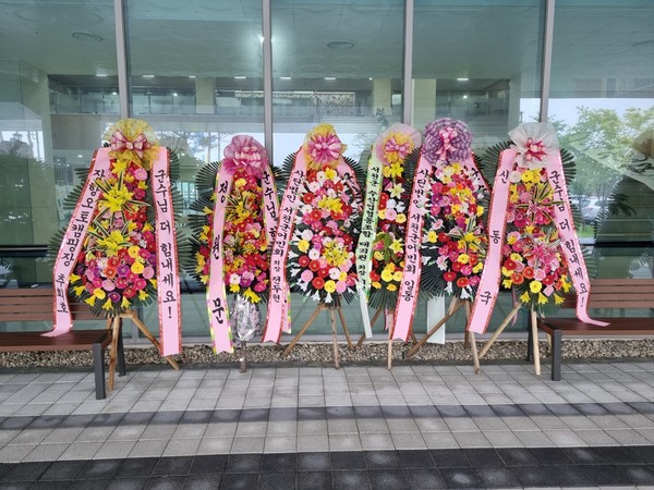 더불어민주당 보령서천지역위원회가 군정농단 등을 이유로 김기웅 서천군수의 사퇴를 촉구하고 있는 가운데 서천군신청사 정문앞에 오히려 김기웅 군수를 응원하는 화환과 화분들이 등장해 관심을 모으고 있다. (사진/ 김정기 기자)