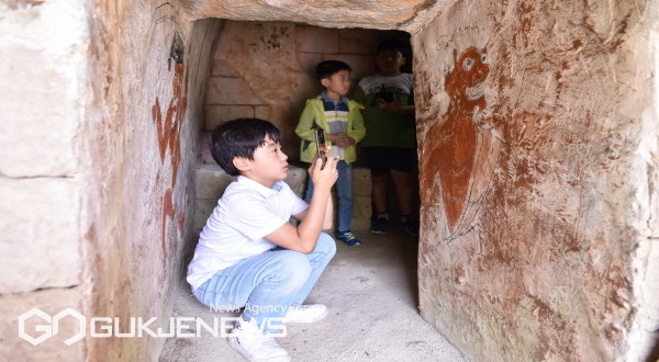 천오백년 벽화고분을 지키는 수호신 프로그램에 참가한 아이가 벽화를 촬영하고 있다
