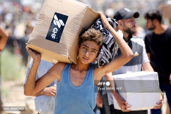 미국이 지원하는 민간 구호단체인 가자인도주의재단(GHF)의 구호물자 상자를 들고 있는 팔레스타인 소년. 사진제공/AFP통신