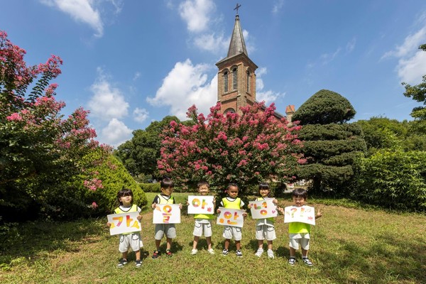 칠곡 가실성당에서 활짝 핀 백일홍 앞에서 왜관읍 동산애 어린이집 원아들이 ‘가을아 안녕’이라는 손피켓을 들고 환하게 웃고 있다.(사진=칠곡군)