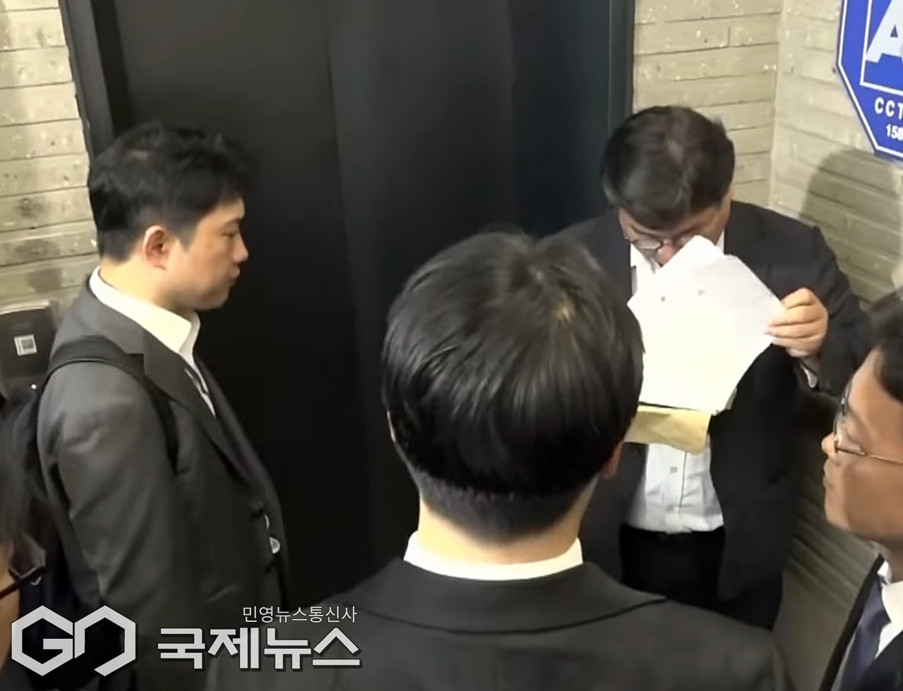 ▲18일 서울 여의도 국민의힘 중앙당사 1층 로비에서 국민의힘 변호인이 특검팀에 제시한 압수수색 영장을 살펴보고 있다./사진=이용우 기자 