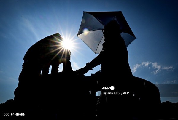 2025년 7월 2일, 더운 여름날 이탈리아 로마의 콜로세움 앞에서 한 사람이 햇빛을 가리기 위해 양산을 들고 걷고 있다. 사진제공/AFP통신